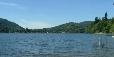 Lake McMurray, surrounded by forested slopes, under a blue sky.