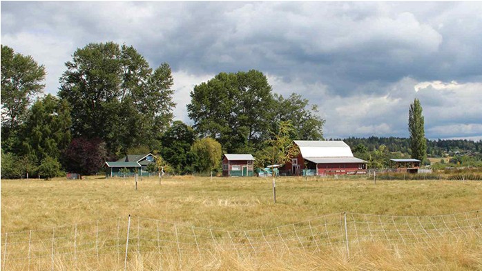 A small farmland parcel with a fenced grassy field and a red barn.