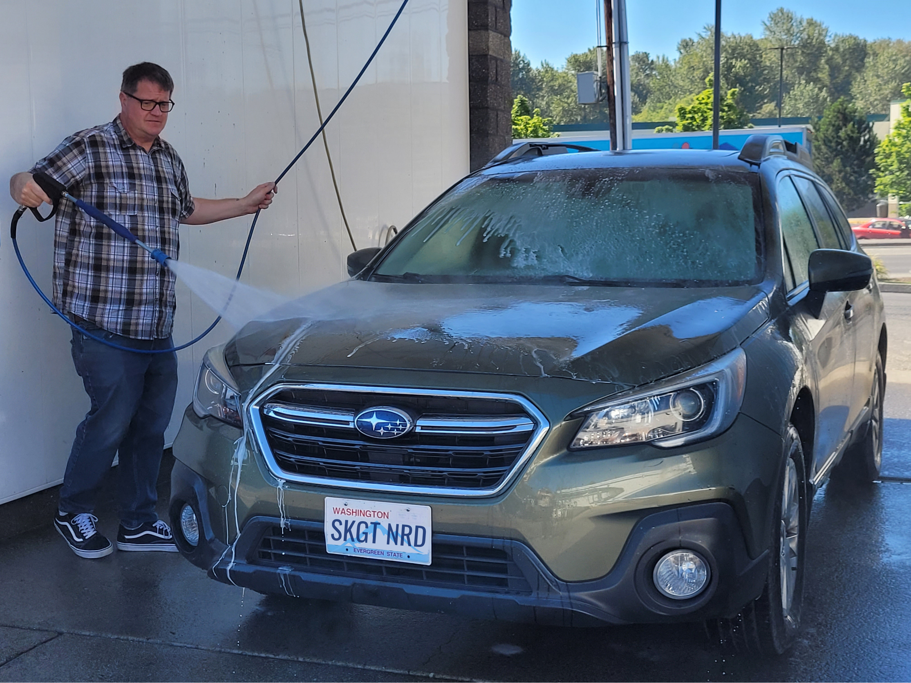 A man sprays a car at a commercial car wash