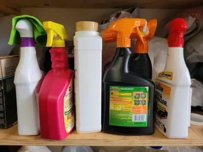 Spray bottles of pesticides and other hazardous waste sit on a garage shelf