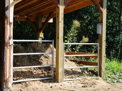 A single-chamber manure storage bin with a roof but no floor is full of manure and bedding.