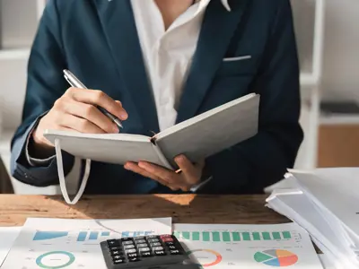 A business person writing in a notebook inside an office