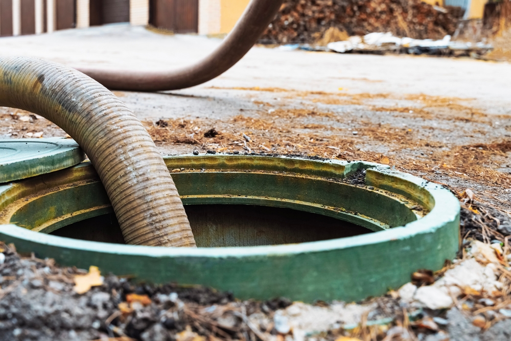 Septic tank in ground being pumped.