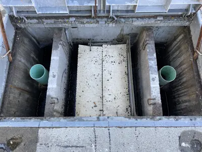 An oil water separator with two chambers and oil absorbing pads inside.